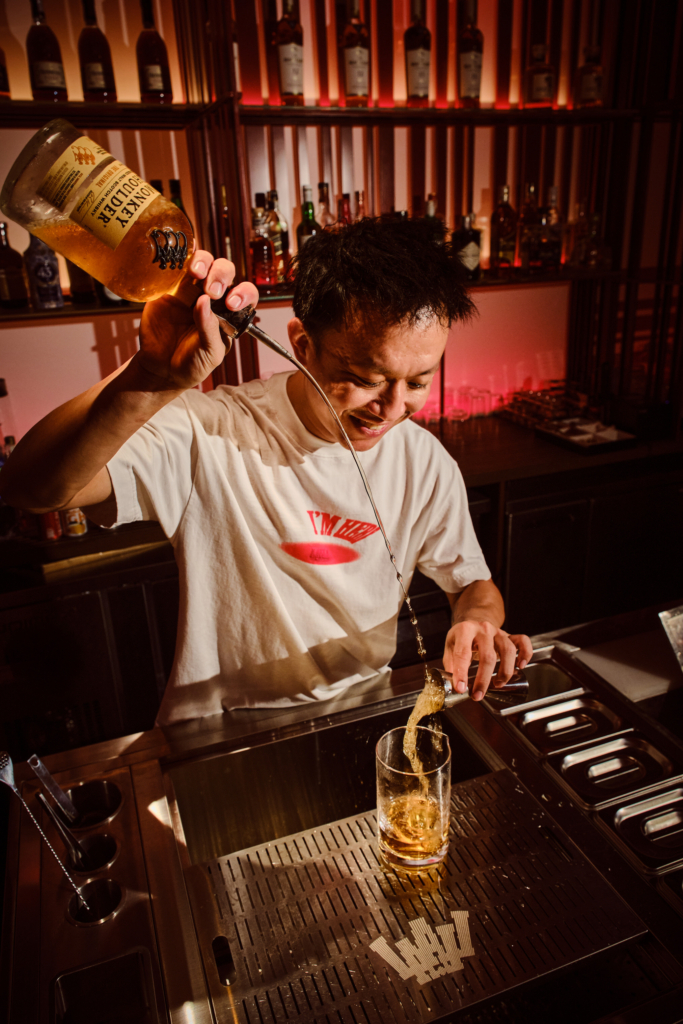 A bartender mid-pour, capturing the rhythm, precision, and quiet joy behind the bar.
