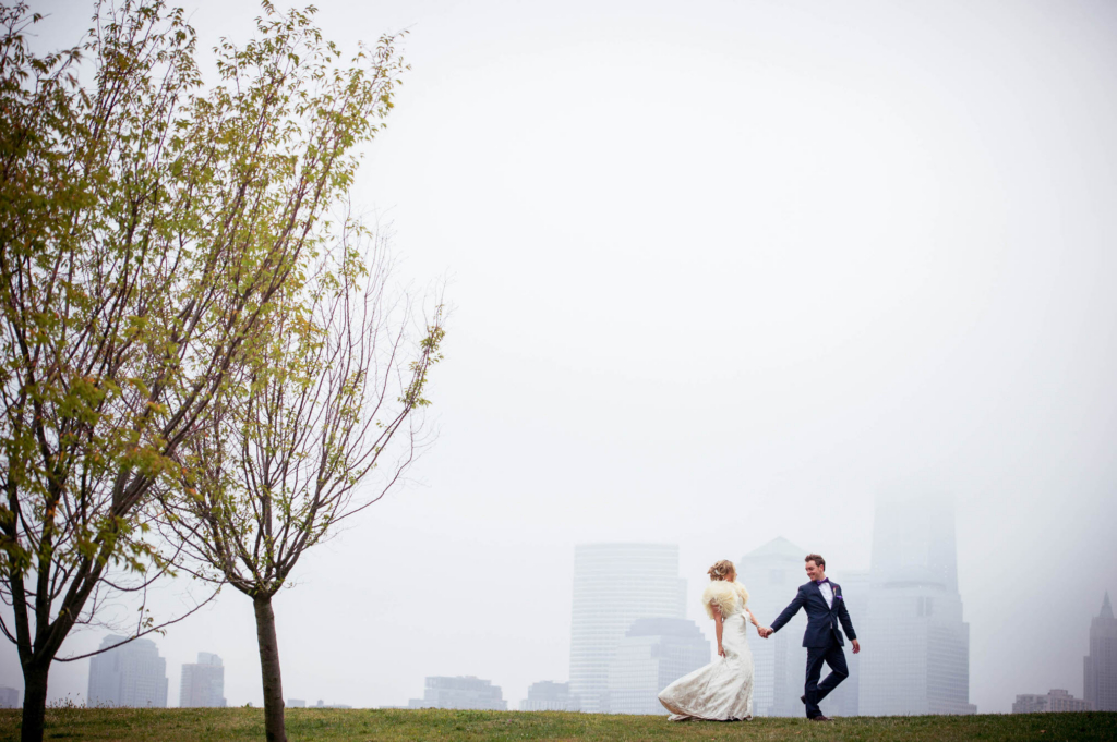 I make no secret of the fact that I love sunny days. I love using the bright, dramatic sun in my wedding portraits. On the day of this 2013 Maritime Parc wedding the sun never made a single appearance. The entire day was cloudy, damp, and with a mist hanging over the Manhattan skyline. During the portrait session of the bride and groom in Liberty State Park I actually adored the weather. What I wanted to be bright and vivid was quiet and muted. I love the dreamy, misty ambience of the images from this portrait session and I especially love the dreamlike appearance of Manhattan in the background of this photograph. Compressed away from the bride and groom by my use of the Nikon 70-200mm lens, the background takes on an almost watercolor look. While this doesn’t reduce my love for the bright sunshine it does strengthen my affection for cloudy days!