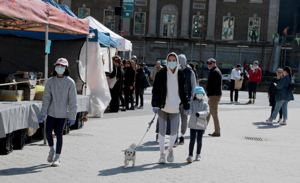New York - MARCH 18, 2020 - An unidentified family wears facial masks Wednesday morning while strolling on the Union Square farmers. As coronavirus infections continue to surge, New York has ordered private businesses to cut on-site workforce by half.