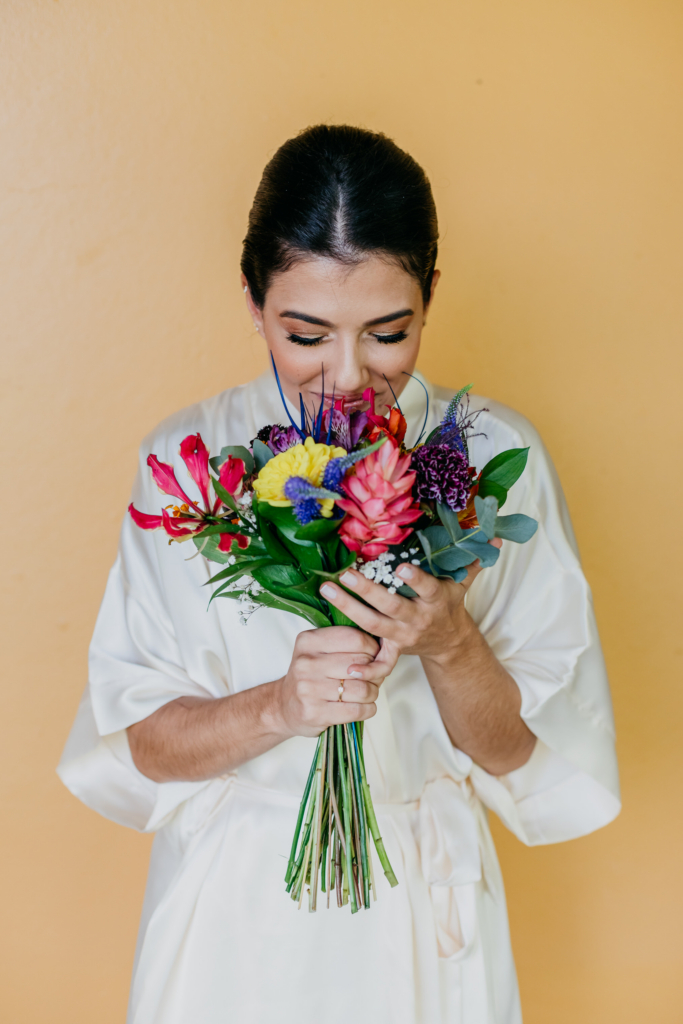 A woman holds a colorful bouquet close to her face, gently smelling the flowers.