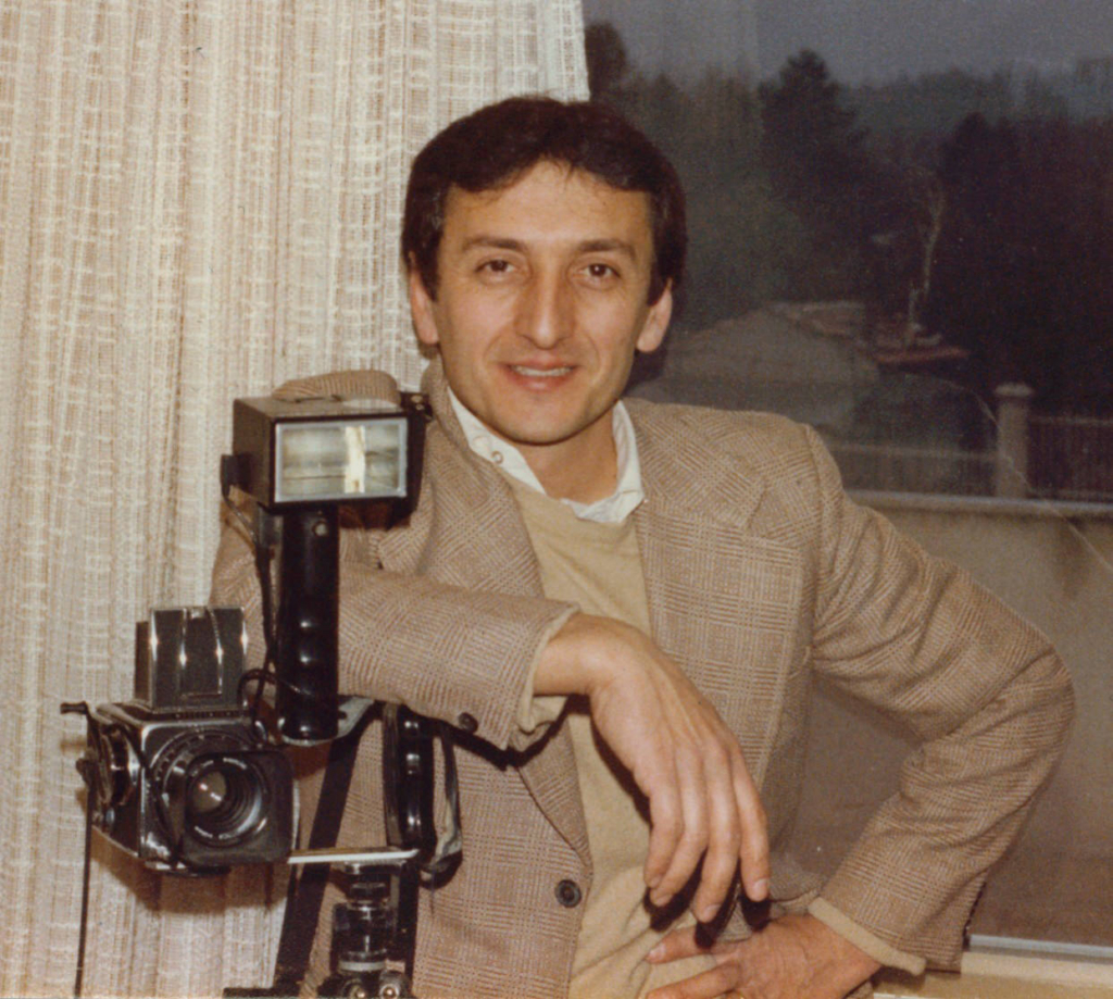 Portrait of the photographer’s father beside a vintage camera, reflecting his early influence in photography.