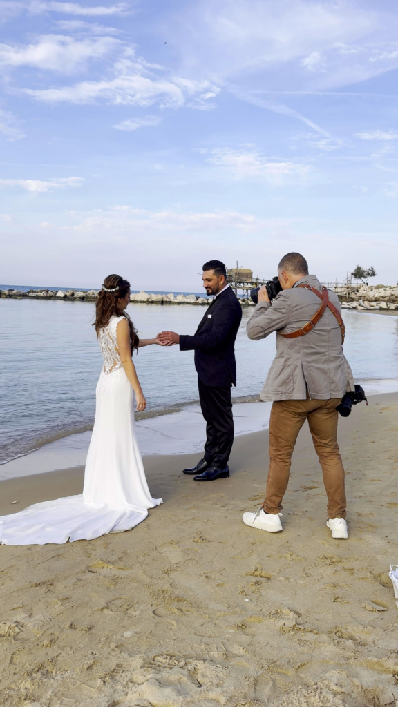 Photographer showing and capturing candid wedding moments with a couple outdoors by the sea.