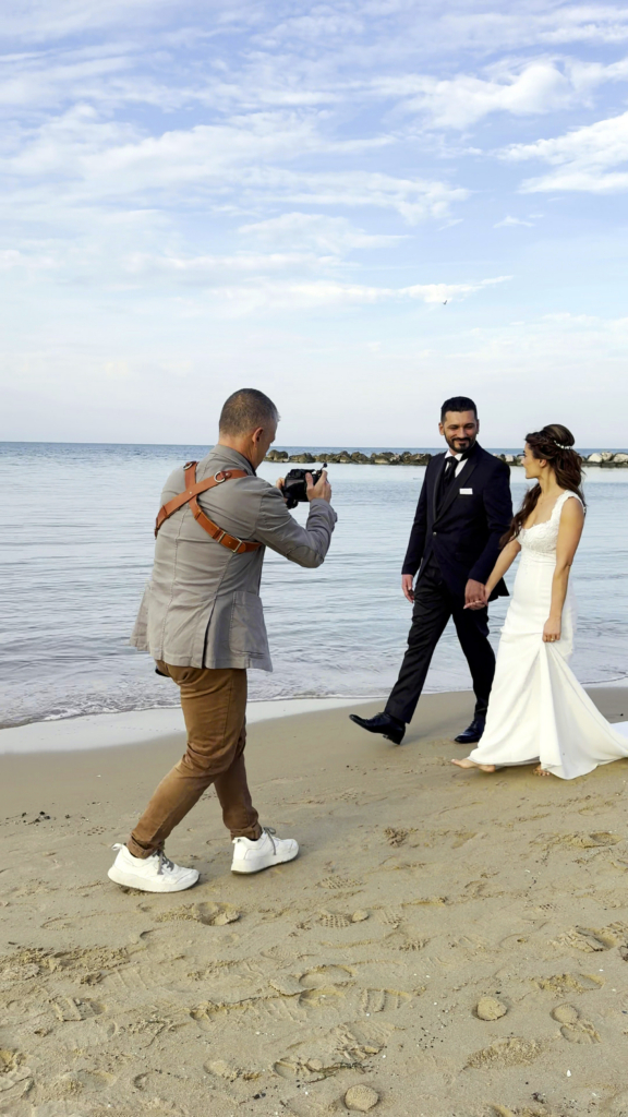 Photographer showing and capturing candid wedding moments with a couple outdoors by the sea.