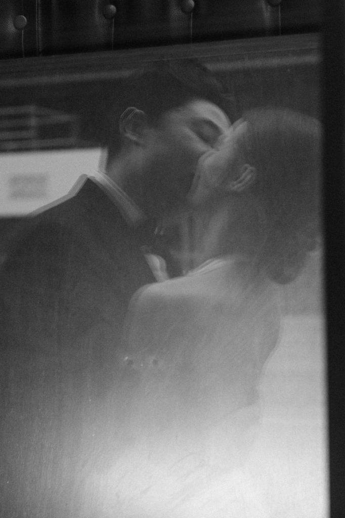 A couple shares a kiss, seen through a soft, blurred surface that creates a dreamy, diffused effect.