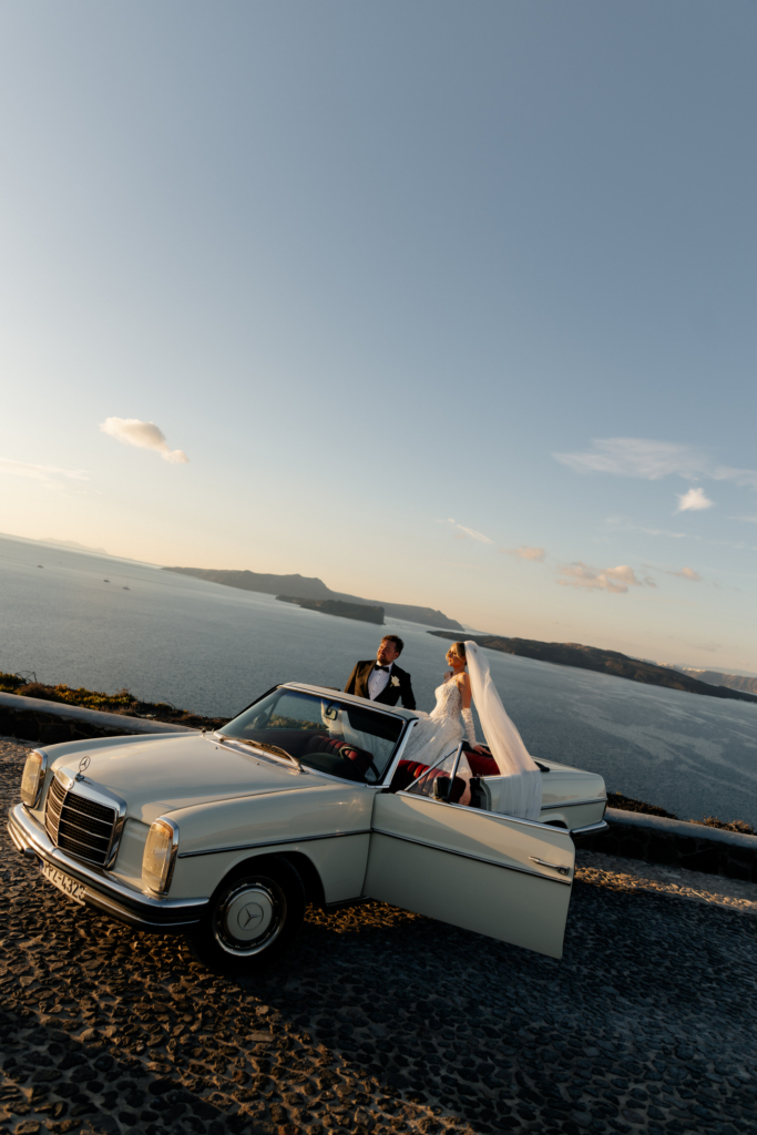 A bride and groom stand beside a vintage white convertible overlooking the sea at golden hour, framed by an expansive coastal horizon.
The warm light, open landscape, and classic car create a cinematic destination wedding portrait with a timeless European feel.