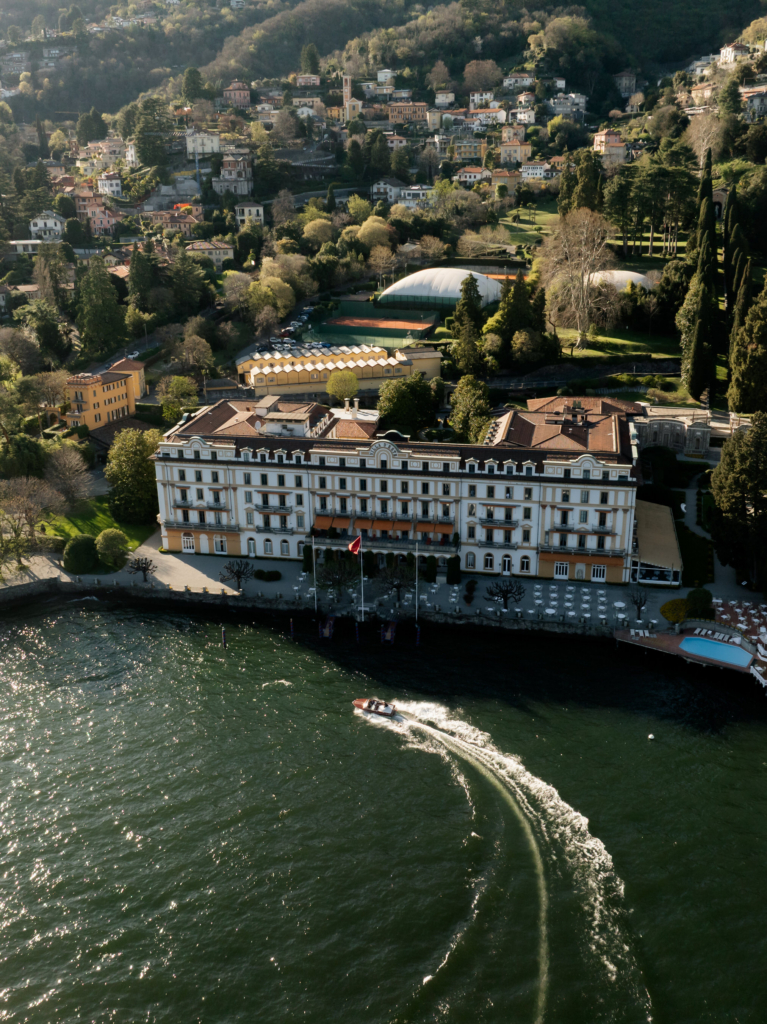An aerial view captures a grand lakeside villa surrounded by lush hills and historic architecture, while a small boat cuts across the water below.
The sweeping perspective and late afternoon light give the scene a timeless, cinematic destination wedding feel.