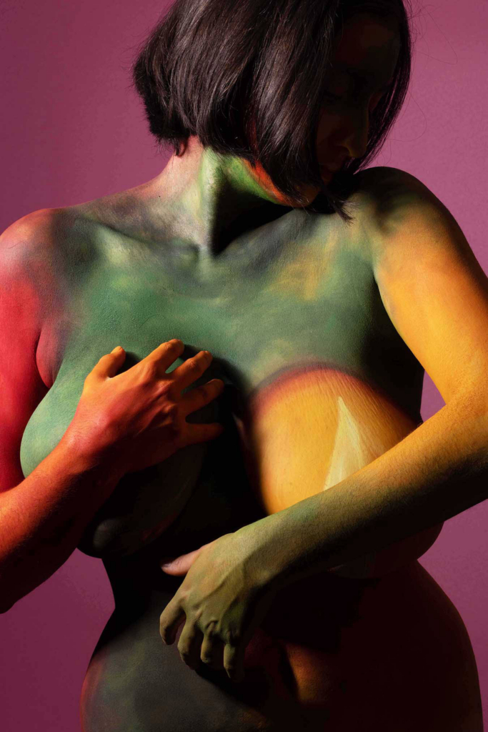 “Abstract nude portrait with dramatic colored lighting and sculptural shadows.”