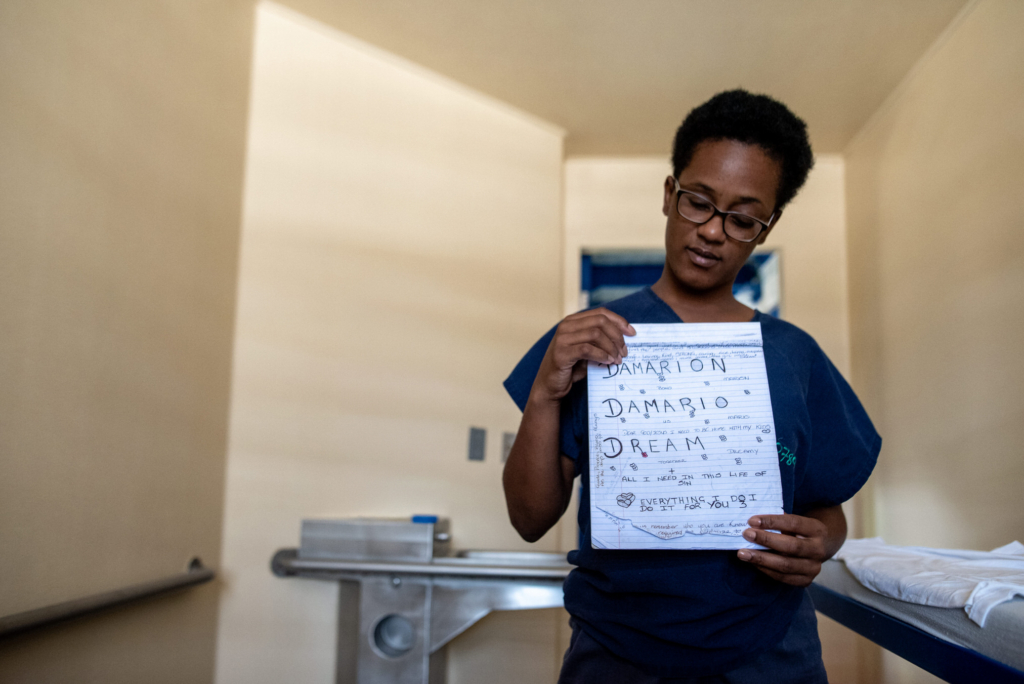 Woman inside a Barbados prison holding a handwritten letter in her cell during a documentary photography project.
