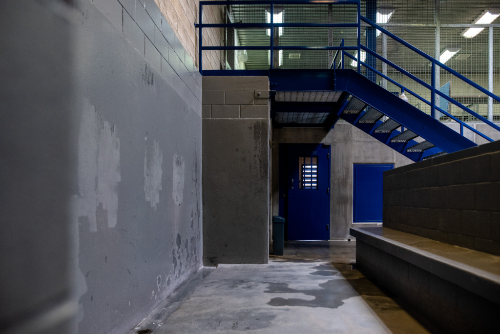 Empty prison corridor with blue metal stairs and concrete walls inside a correctional facility in Barbados.