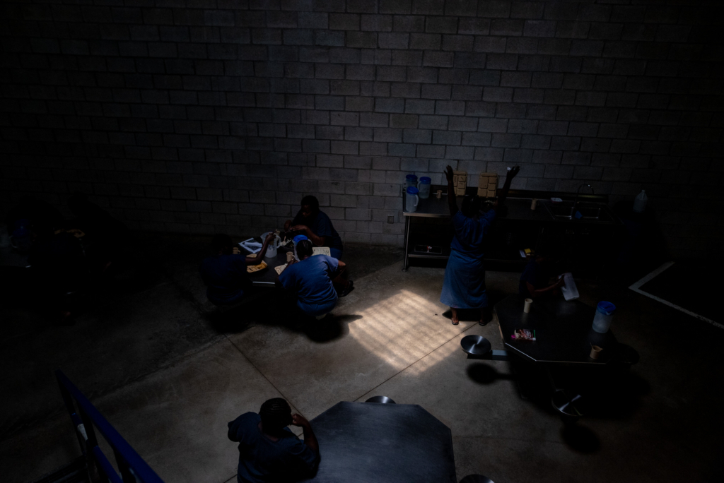 Women inside a Barbados prison gathered in a dimly lit common area during a documentary photography project.
