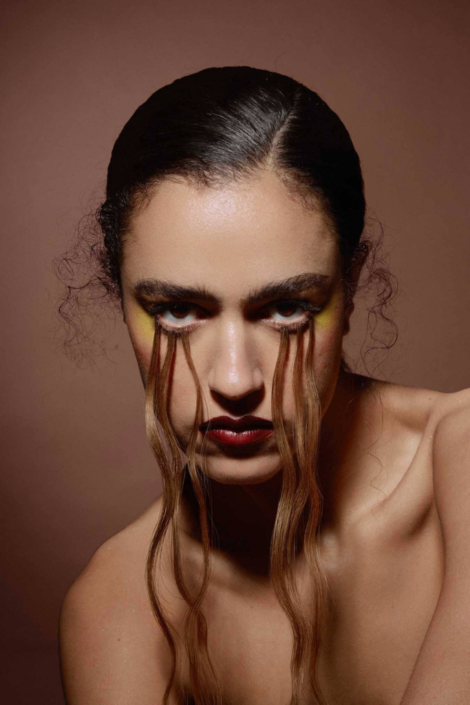 Avant-garde beauty portrait with sculptural hair styling and emotionally intense gaze.