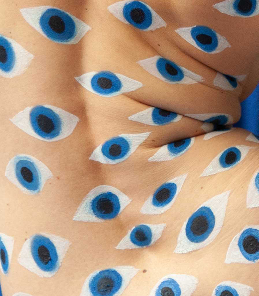 Surreal body painting composition covered in repeated blue eye motifs and organic body contours.